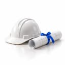 A white hard hat beside a rolled blueprint tied with a blue ribbon