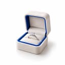 A solitaire ring inside an open jewellery box lined in blue